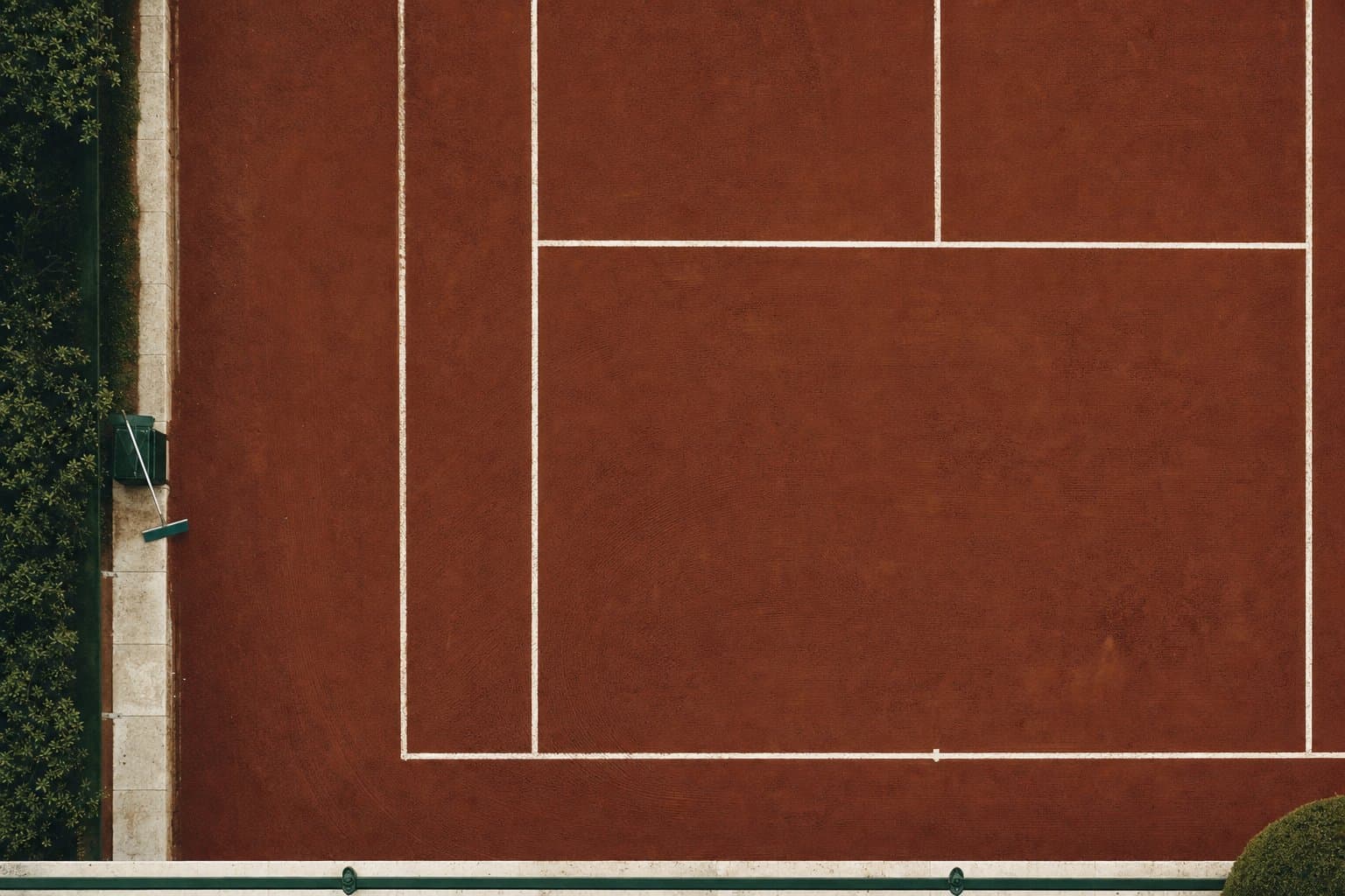 A clay court baseline and service lines seen from above, chalk-white lines on crushed brick.